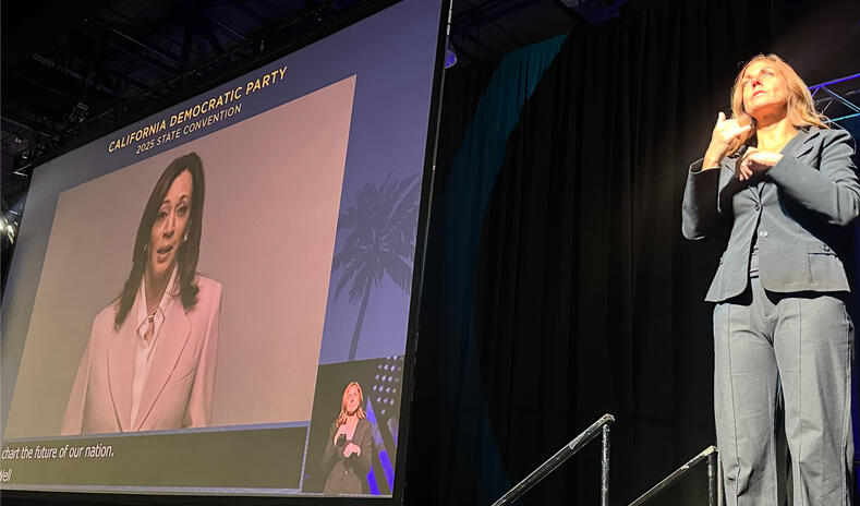Kamala Harris on projected on large screen with interpreter in the corner