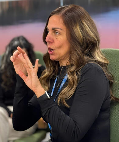 interpreter in black, hands in the air with a visitor badge around her neck